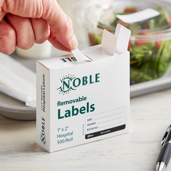 A hand putting a Noble Products hospital label on a white box.