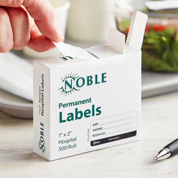 A person's hand putting a Noble permanent label on a white box.