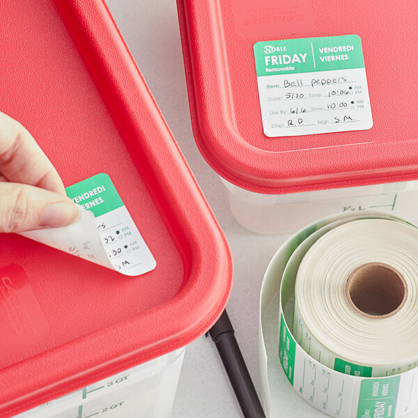 A hand using a Noble Products Friday food label to label a red container.