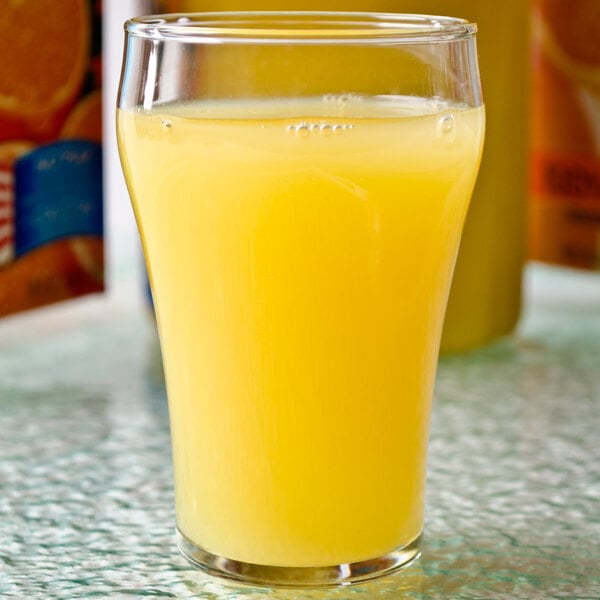 A Libbey customizable soda glass filled with orange juice on a table.