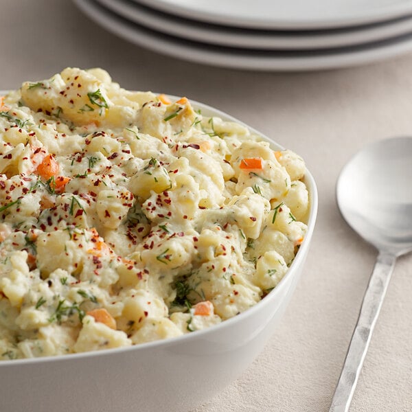 A bowl of potato salad with a spoon on the side.
