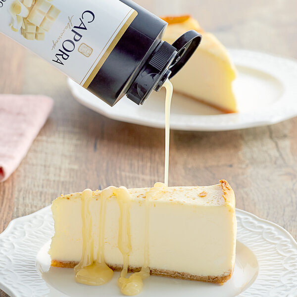 A cheesecake with Capora White Chocolate Sauce being poured onto it.