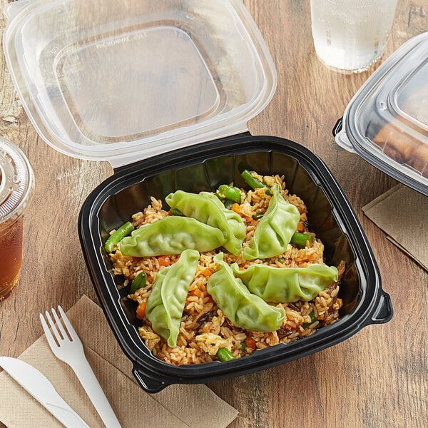 A black plastic Choice container with rice and vegetables in it on a table.