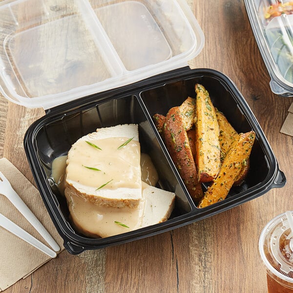 A black Choice plastic container with turkey and gravy in one compartment and food in the other.