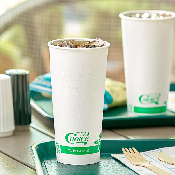 Two EcoChoice Compostable PLA paper cold cups filled with ice on a tray with a wooden fork and knife.