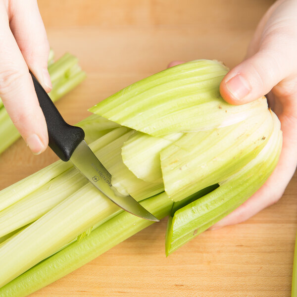 A person using a Victorinox Bird's Beak Paring Knife to peel celery.
