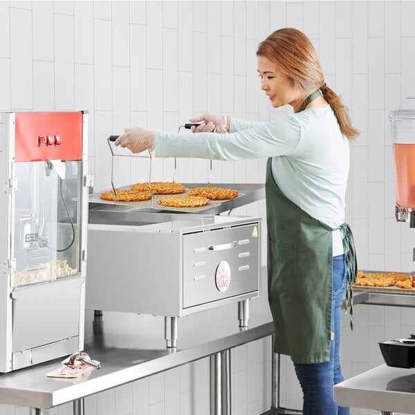 A woman using a Carnival King countertop fryer to make funnel cakes in a commercial kitchen.