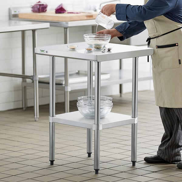 A chef preparing food on a Regency stainless steel work table with galvanized undershelf.