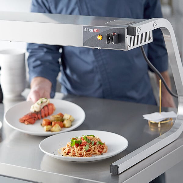 A chef using a ServIt strip warmer to heat food on a table.