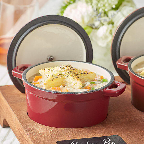 A red Valor Merlot enameled cast iron pot with a cover and food inside.