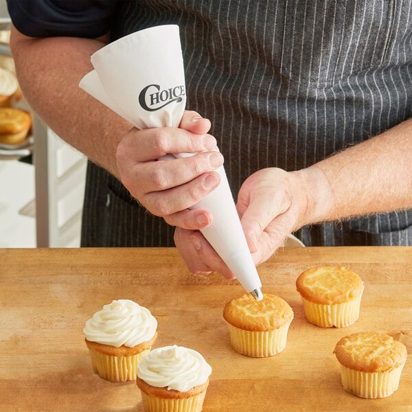 A person using a Choice Plastic Coated Canvas pastry bag to frost cupcakes.
