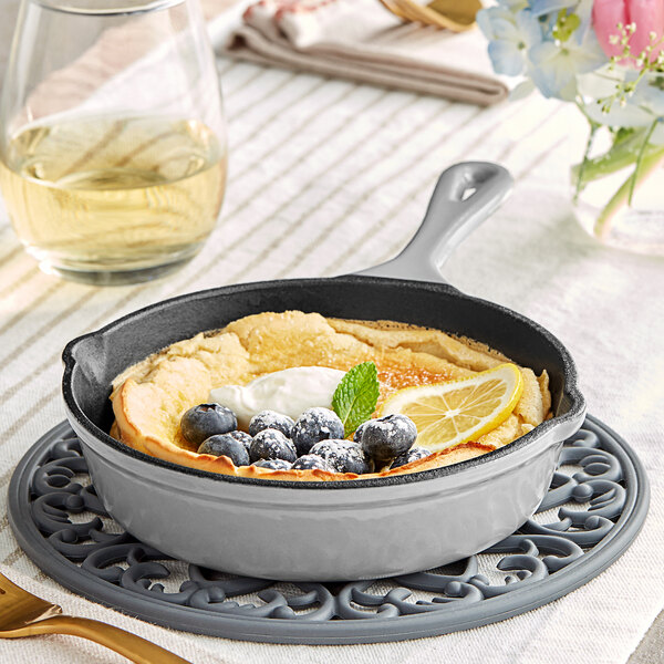 A Valor slate grey enameled mini cast iron skillet with blueberries and lemon slices cooking in it on a table.