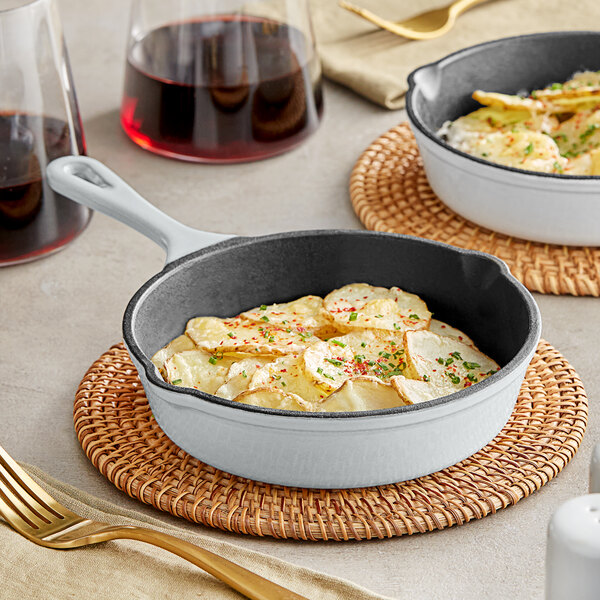 A Valor enameled cast iron skillet with potato chips on a table with wine.