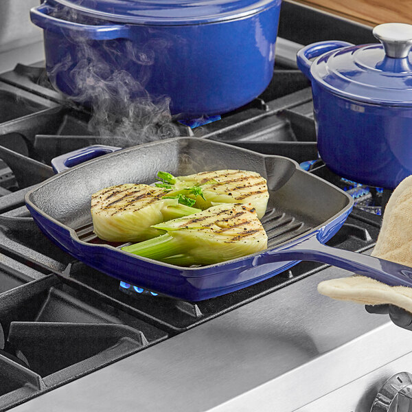 A person using a Valor Galaxy Blue enameled cast iron grill pan to cook food on a stove.