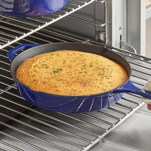 A Valor Galaxy Blue enameled cast iron skillet with cornbread in it on a table in a home kitchen.