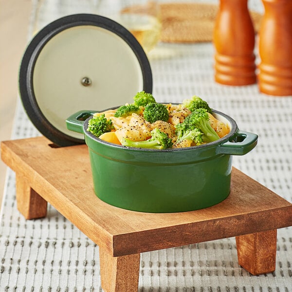 A Valor fern green enameled cast iron pot with broccoli and cheese on a table.