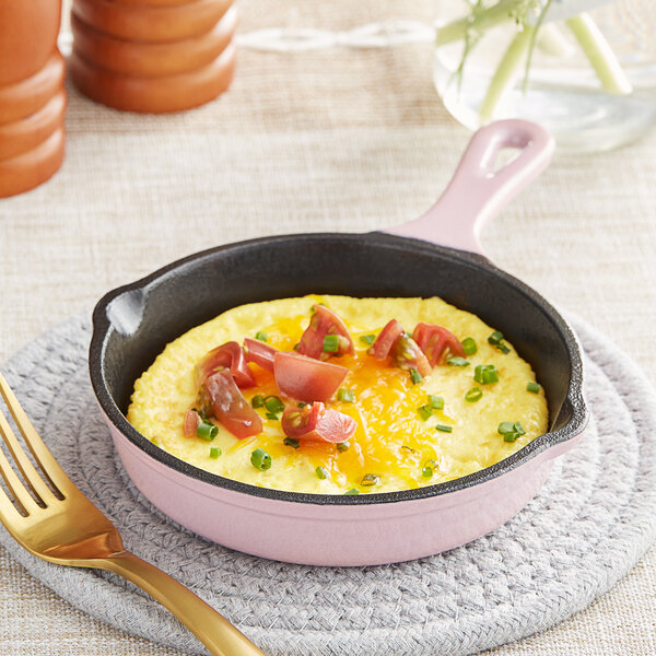 A Valor enameled cast iron skillet with an omelette topped with tomatoes and green onions.