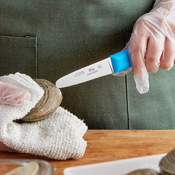 A person in plastic gloves using a Choice stainless steel clam knife with a blue handle to open a clam shell.