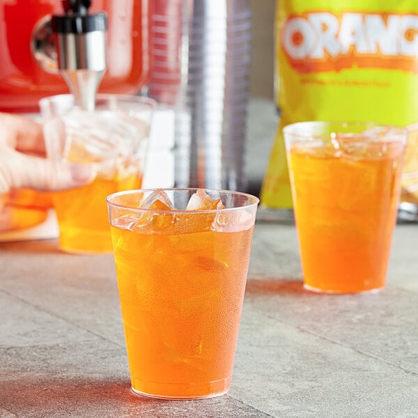 A plastic cup of DominAde orange drink mix with ice.