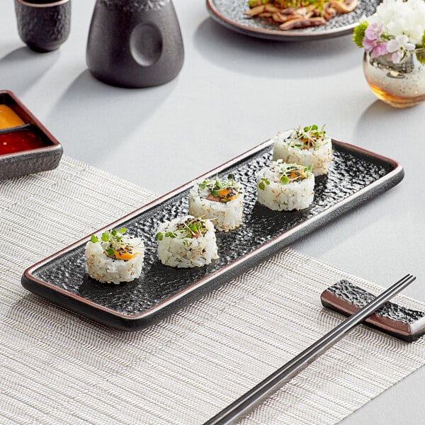 A rectangular black Acopa stoneware plate with sushi on it.