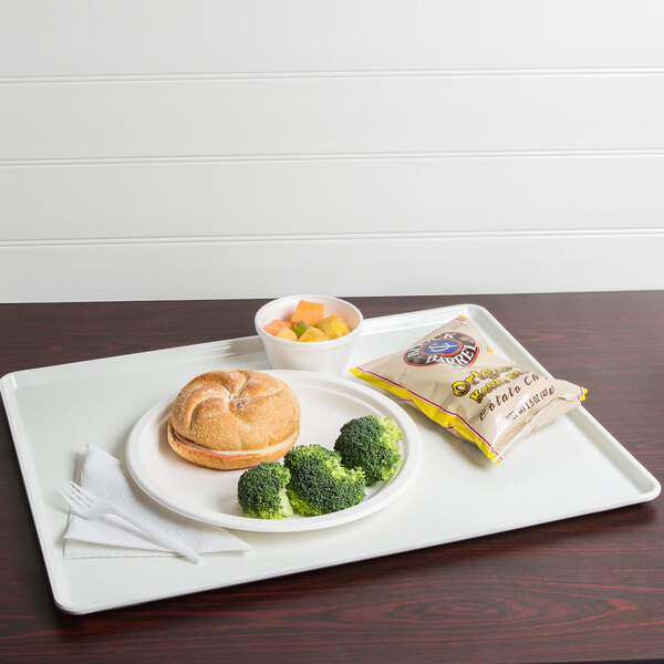 A white Cambro dietary tray with a sandwich, broccoli, and fruit on it.