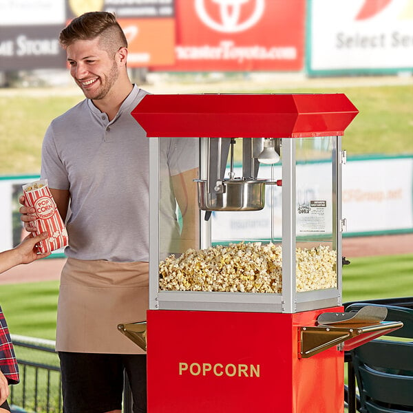 A man and woman standing next to a Carnival King Kettle Corn Popcorn Popper.
