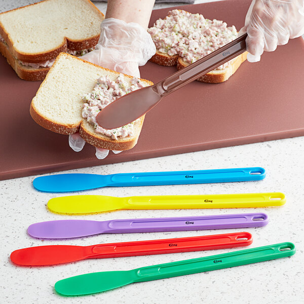 A hand using a Choice sandwich spreader to spread on a sandwich.