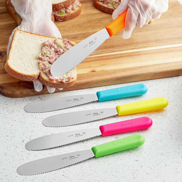 A person spreading food on a piece of bread with a yellow, blue, and pink and green Choice sandwich spreader.