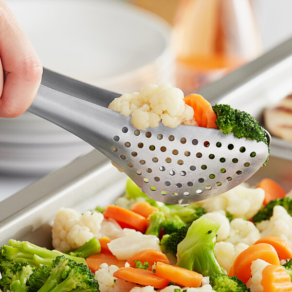 A person using American Metalcraft stainless steel serving tongs to serve vegetables.
