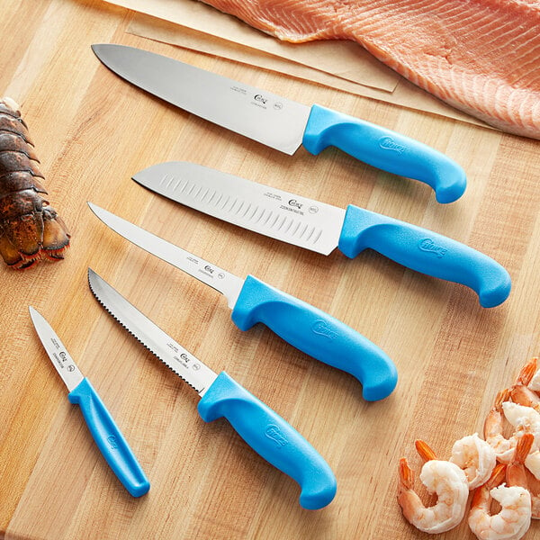 A Choice 5-piece knife set with blue handles on a wooden surface with shrimp.