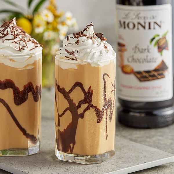 Two glasses of chocolate milkshakes with whipped cream and Monin Premium Dark Chocolate syrup.
