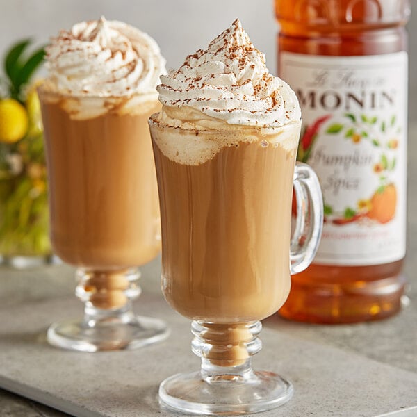 Two glasses of Monin Pumpkin Spice coffee with whipped cream and cinnamon.