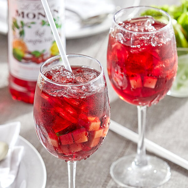 Two glasses of Monin Premium Red Sangria with straws and ice cubes.