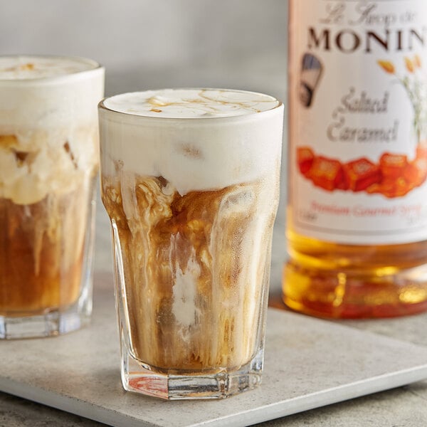 A glass of iced coffee with Monin Salted Caramel Flavoring Syrup on a table.