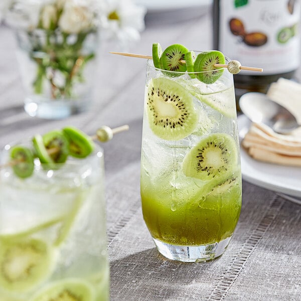 A glass of Monin kiwi-flavored drink with kiwi slices on the rim.