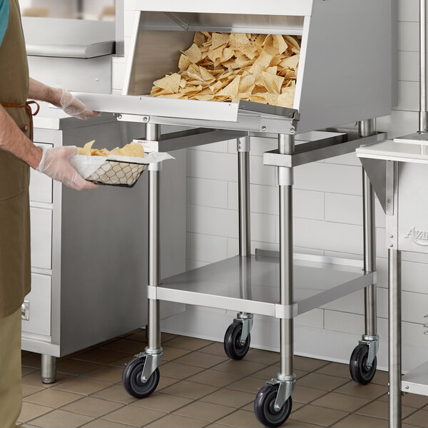 A man using a ServIt portable stand to hold a basket of chips over a counter.