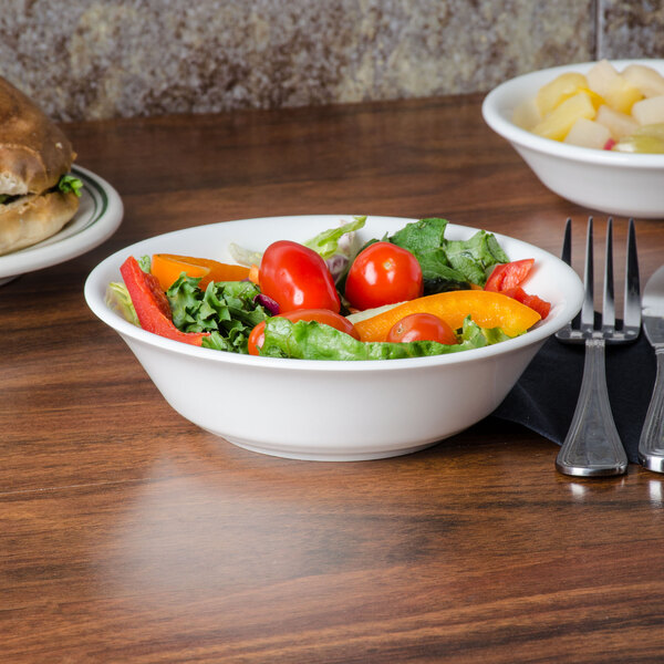 A bowl of salad with tomatoes and lettuce on a table.
