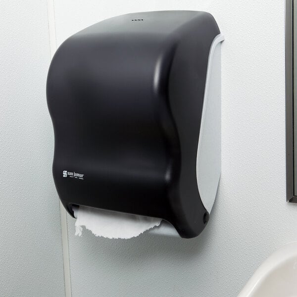 A black San Jamar Tear-N-Dry paper towel dispenser on a white wall.