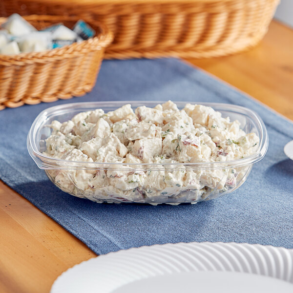 A Visions clear plastic bowl filled with potato salad on a table.