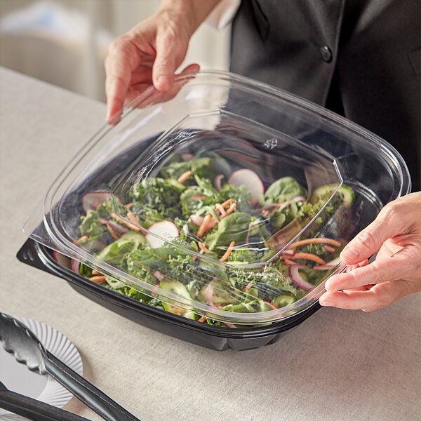 A person holding a Visions plastic container of salad.