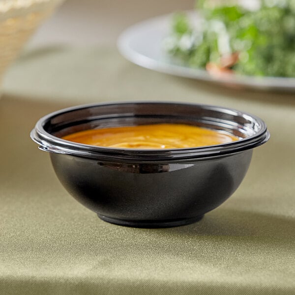 A black Visions plastic bowl of soup on a table.