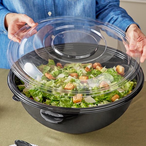 A woman holding a Visions clear plastic dome lid over a salad bowl.