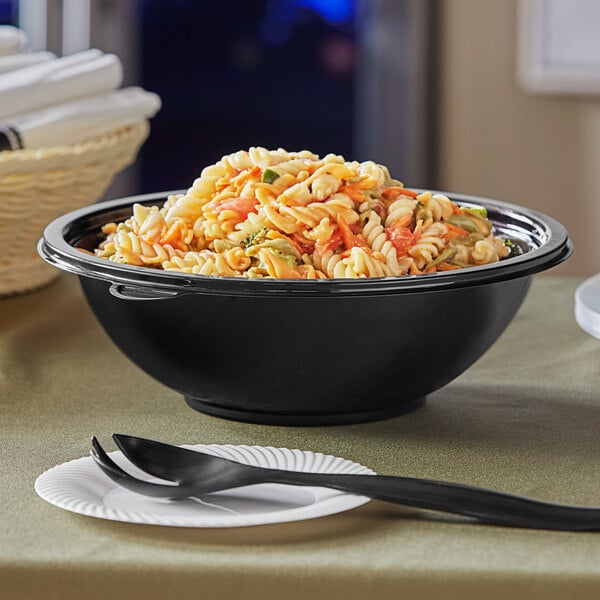 A Visions black plastic bowl filled with pasta and a spoon.