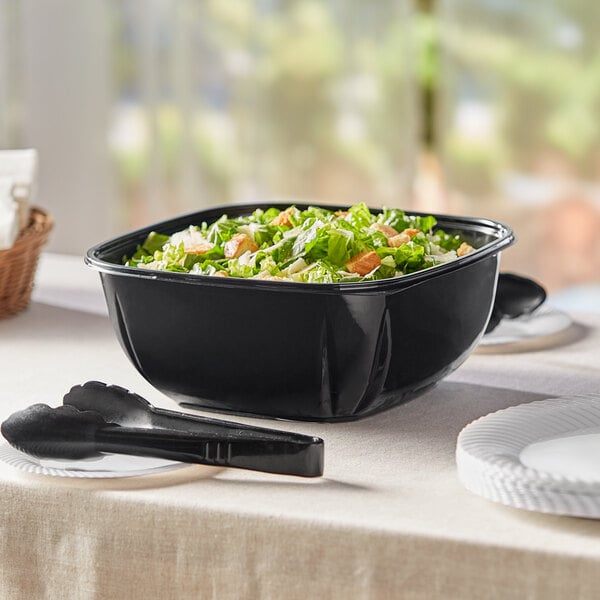 A black Visions catering bowl filled with salad on a table.