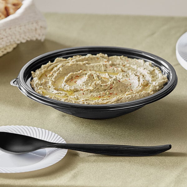 A Visions black plastic bowl filled with hummus on a table.