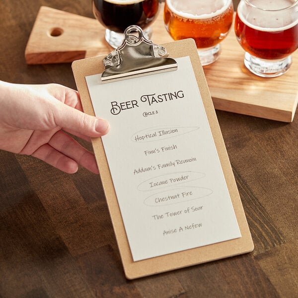 A hand holding a Choice hardback menu on a clipboard next to a glass of beer.