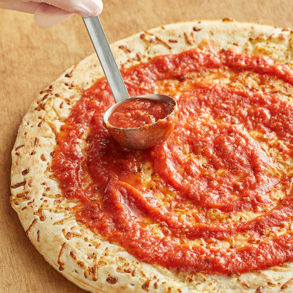 A person using a spoon to spread Dei Fratelli pizza sauce on a pizza.