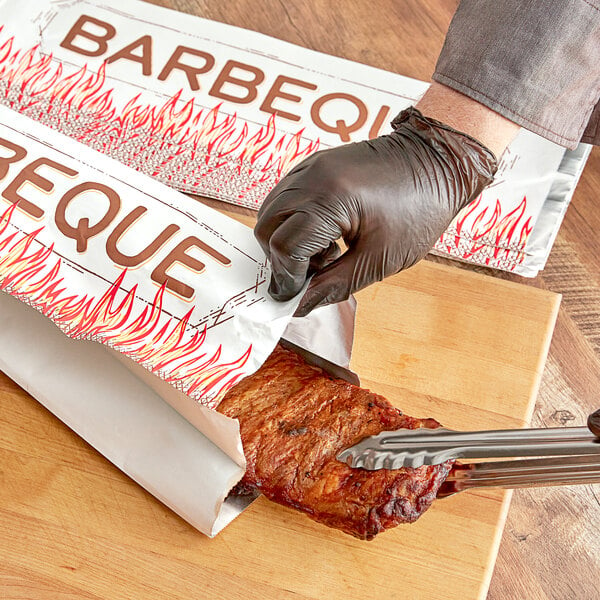 A person cutting meat in an insulated foil bag with a gloved hand.