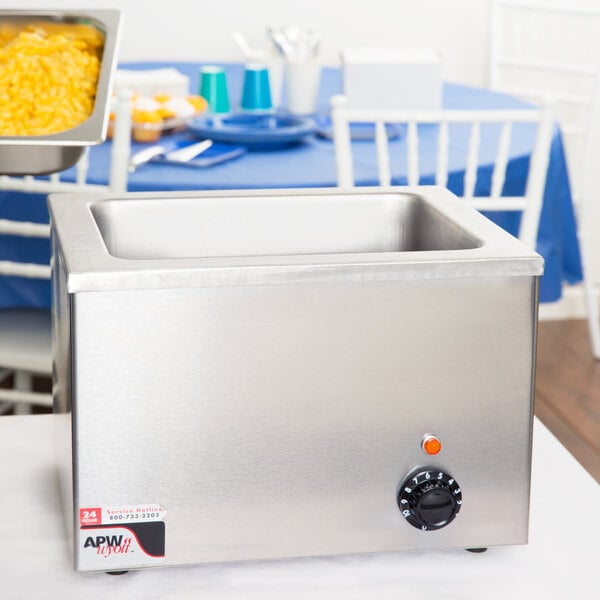 An APW Wyott stainless steel countertop food warmer with a tray of food.
