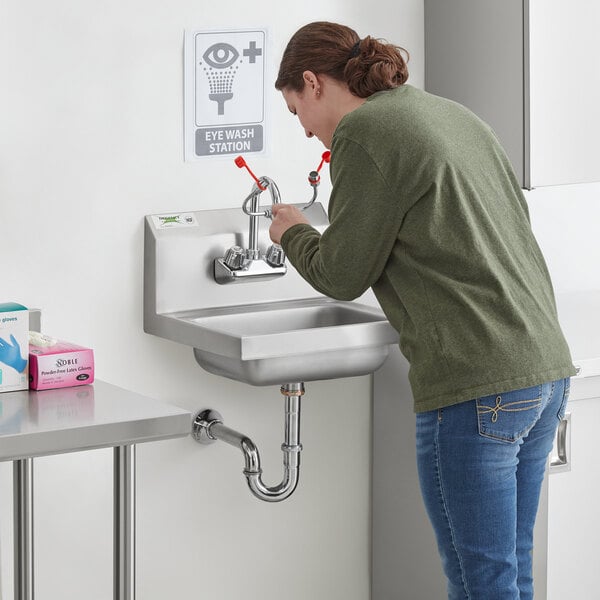 A woman using a wall mounted Regency hand sink.